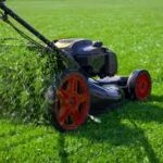 A lawnmower cutting grass in a green yard.