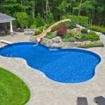 Backyard pool with waterslide and surrounding garden.