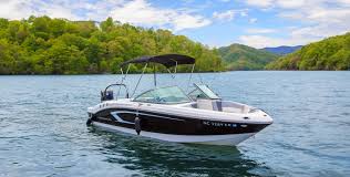 A sleek motorboat floating on a calm lake with green hills in the background.