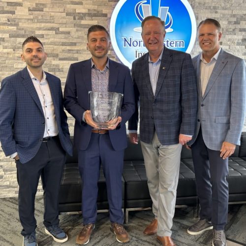 Four men in suits holding glass award